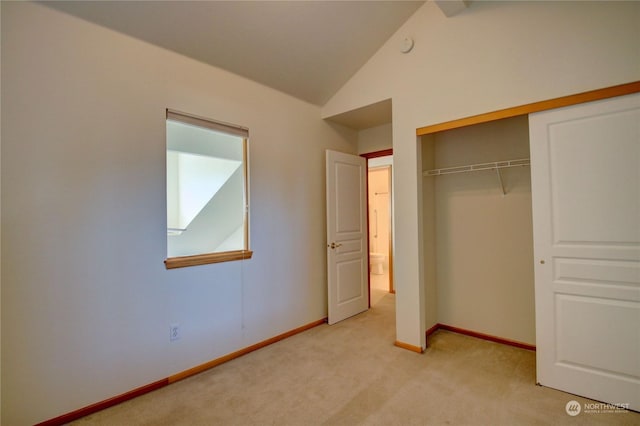 unfurnished bedroom with lofted ceiling, light carpet, and a closet