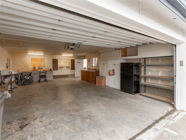 garage with a garage door opener, electric panel, and black fridge