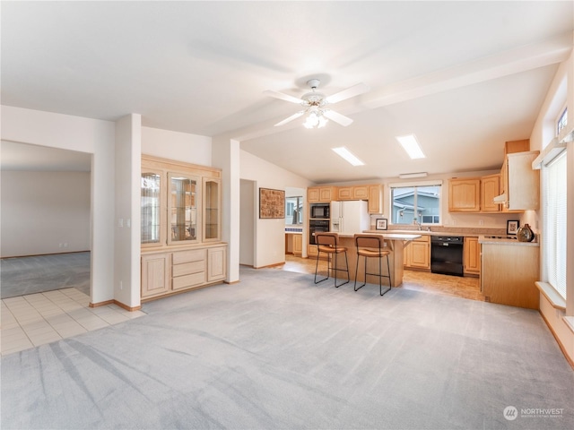 kitchen with ceiling fan, a center island, light brown cabinetry, a breakfast bar, and black appliances