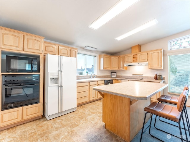 kitchen with a breakfast bar, light brown cabinets, a center island, and black appliances