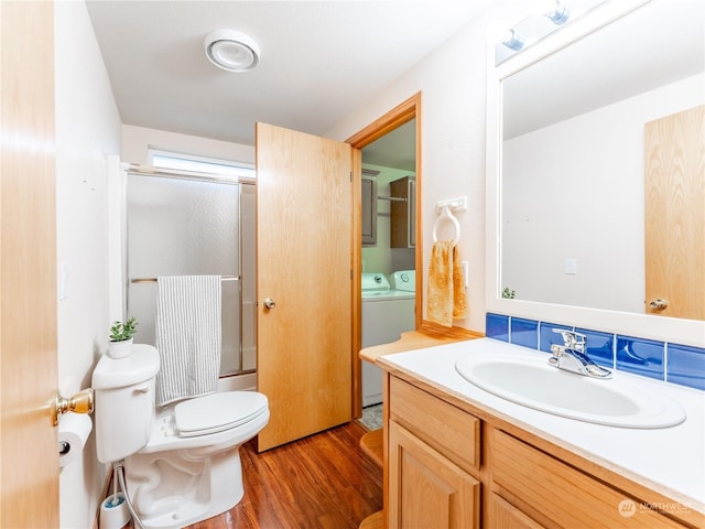 full bathroom with enclosed tub / shower combo, toilet, washer and clothes dryer, vanity, and hardwood / wood-style flooring