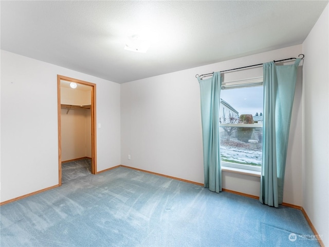 unfurnished bedroom featuring a walk in closet, a closet, and carpet floors