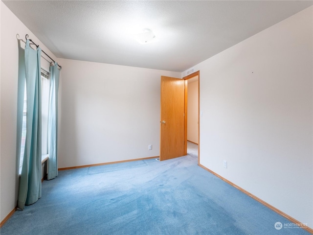 carpeted spare room with a textured ceiling