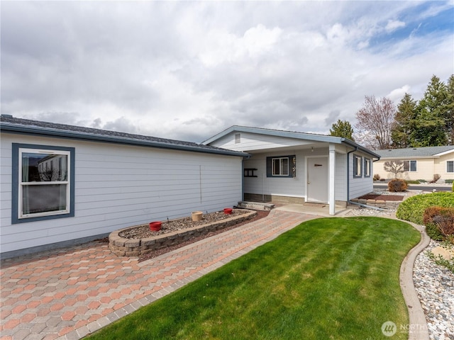 back of house with a patio and a lawn