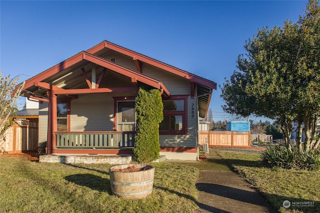 view of front of house featuring covered porch, a front yard, and central AC