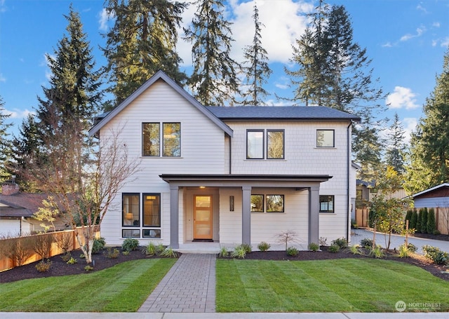 modern farmhouse style home featuring a porch, a front yard, and fence