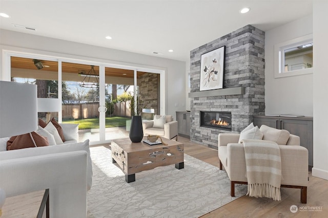 living room with light hardwood / wood-style flooring and a stone fireplace