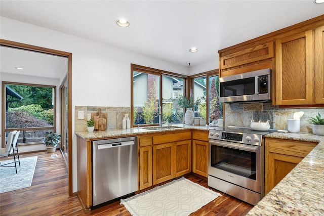 kitchen with backsplash, sink, appliances with stainless steel finishes, dark hardwood / wood-style flooring, and light stone counters