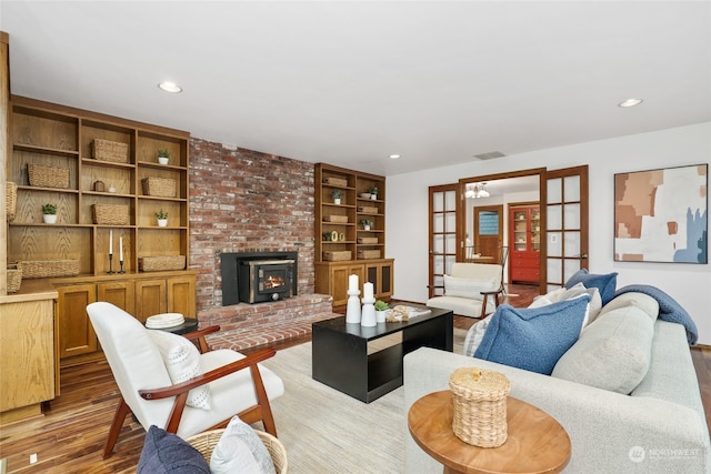 living room with light hardwood / wood-style floors, a wood stove, french doors, and built in shelves