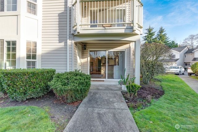 entrance to property featuring a yard and a balcony