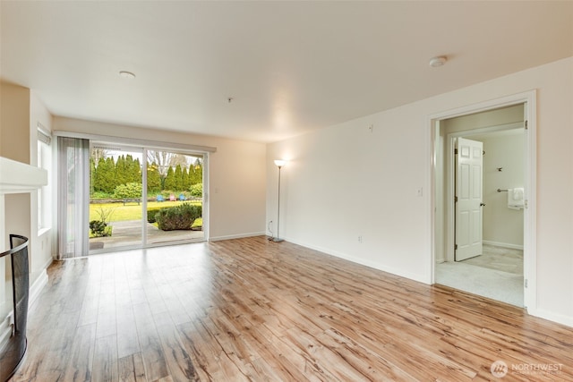 unfurnished living room featuring light wood-type flooring, a fireplace, and baseboards