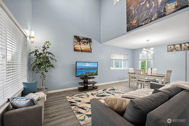 living room featuring hardwood / wood-style floors, a towering ceiling, and a notable chandelier