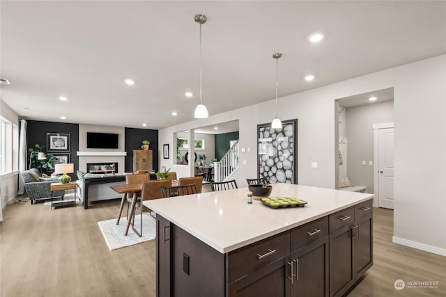 kitchen with dark brown cabinets, a kitchen island, light wood-type flooring, and hanging light fixtures