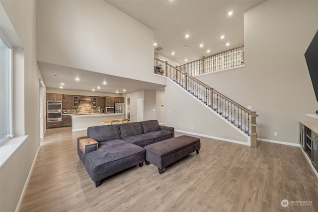 living room with light hardwood / wood-style floors, sink, and a high ceiling