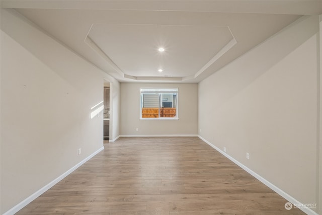 spare room featuring a tray ceiling and light hardwood / wood-style flooring