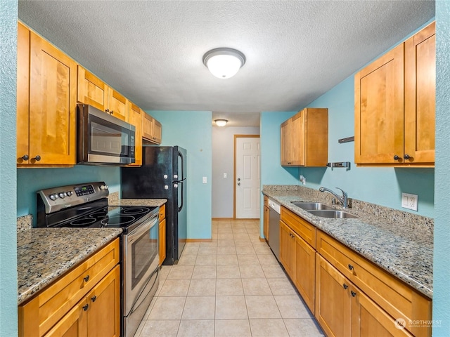 kitchen featuring light stone countertops, a textured ceiling, stainless steel appliances, and sink