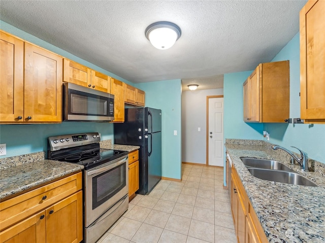 kitchen featuring stone counters, sink, light tile patterned floors, a textured ceiling, and stainless steel appliances