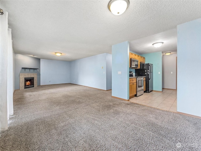 unfurnished living room featuring a textured ceiling, light colored carpet, and a fireplace