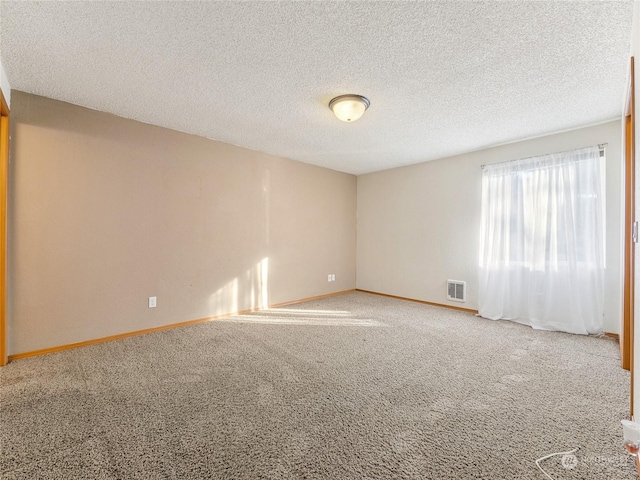 spare room with light colored carpet and a textured ceiling