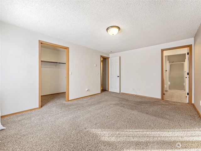 unfurnished bedroom with a spacious closet, a closet, carpet floors, and a textured ceiling