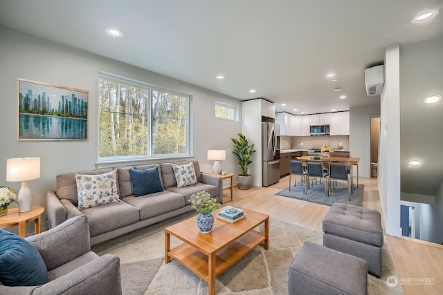 living room with a wall mounted AC and light hardwood / wood-style flooring