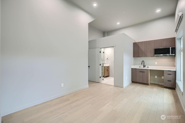 kitchen featuring sink, a towering ceiling, and light hardwood / wood-style floors