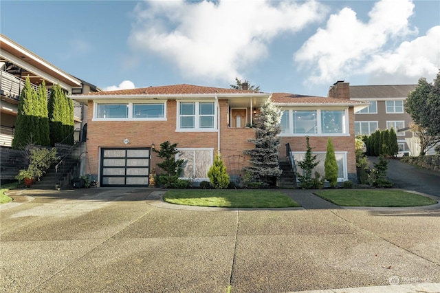 view of front of house with stairs, concrete driveway, brick siding, and an attached garage