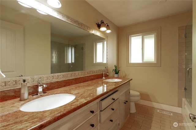 full bathroom featuring toilet, a shower with door, and a sink