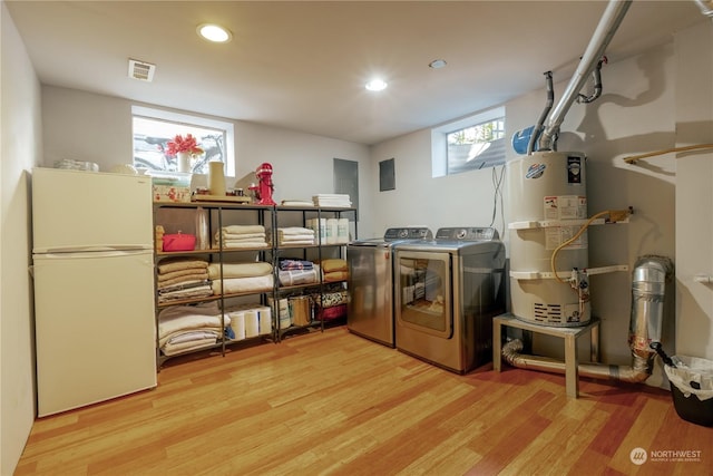 laundry room with laundry area, visible vents, light wood-style flooring, washing machine and dryer, and water heater