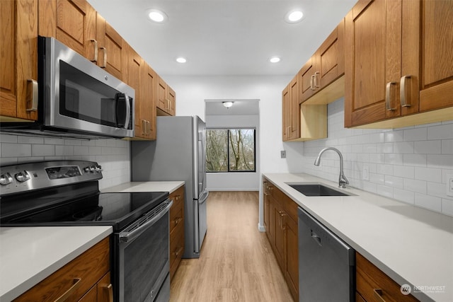 kitchen featuring decorative backsplash, sink, light wood-type flooring, and appliances with stainless steel finishes