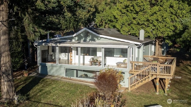 rear view of property featuring a yard and a sunroom