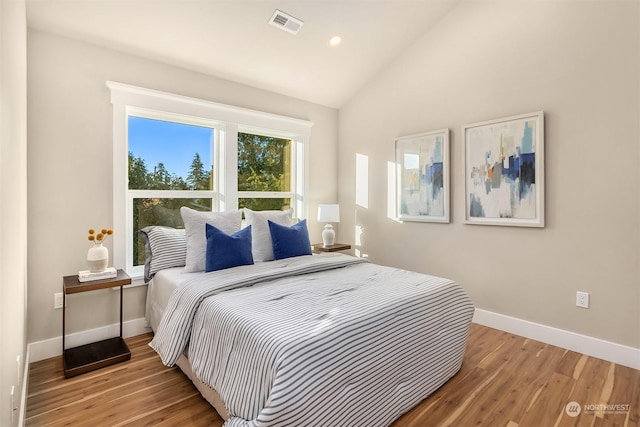 bedroom with light wood-type flooring and vaulted ceiling