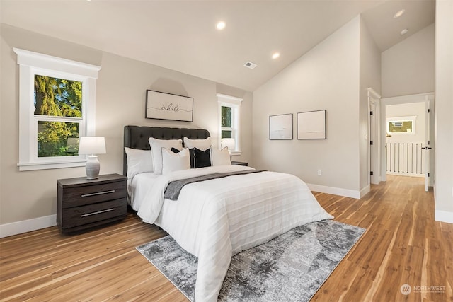 bedroom featuring high vaulted ceiling and light hardwood / wood-style flooring