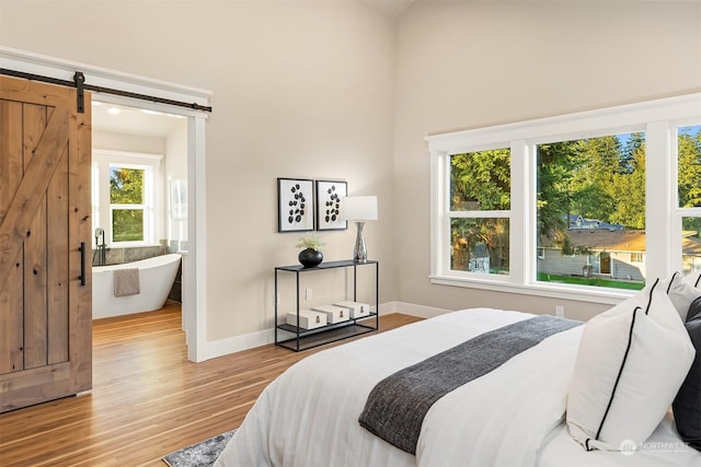 bedroom with light wood-type flooring and a barn door