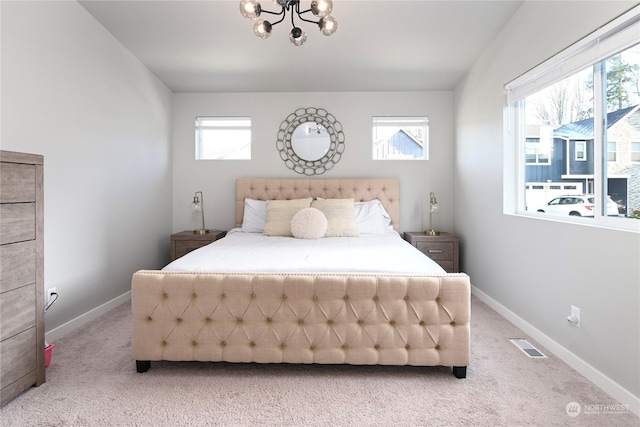 carpeted bedroom featuring multiple windows and a notable chandelier