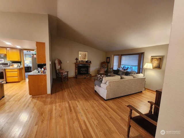 living room with light wood-type flooring, a wood stove, and lofted ceiling