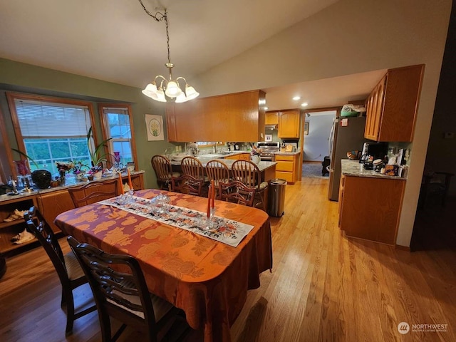 dining area featuring light hardwood / wood-style floors, lofted ceiling, and a notable chandelier