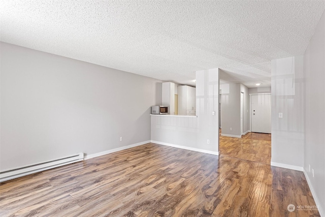 empty room featuring hardwood / wood-style floors, a textured ceiling, and a baseboard heating unit