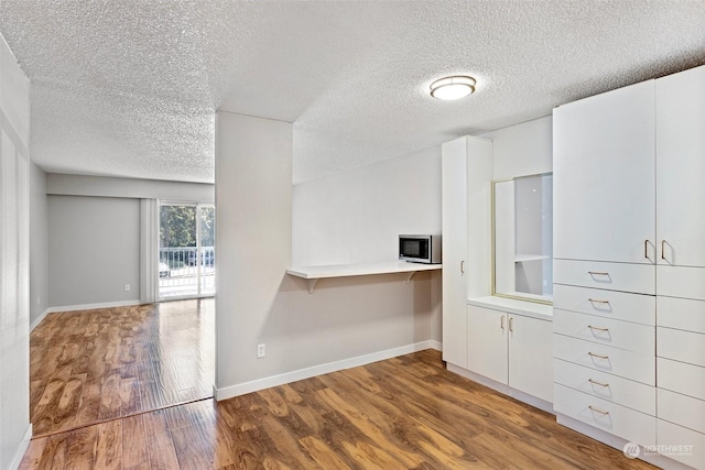 kitchen featuring white cabinets, a textured ceiling, and hardwood / wood-style flooring