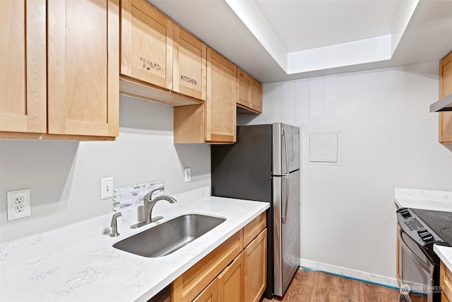 kitchen with sink, light wood-type flooring, light brown cabinets, and appliances with stainless steel finishes