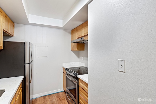 kitchen featuring appliances with stainless steel finishes, light hardwood / wood-style flooring, a raised ceiling, and light brown cabinetry