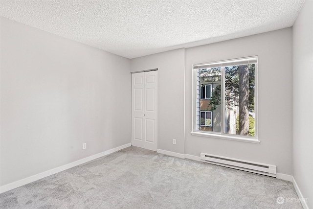 carpeted empty room with baseboard heating and a textured ceiling