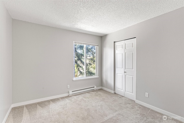 carpeted spare room with a textured ceiling and baseboard heating