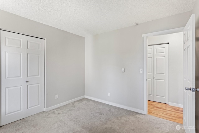 unfurnished bedroom featuring a textured ceiling and light colored carpet