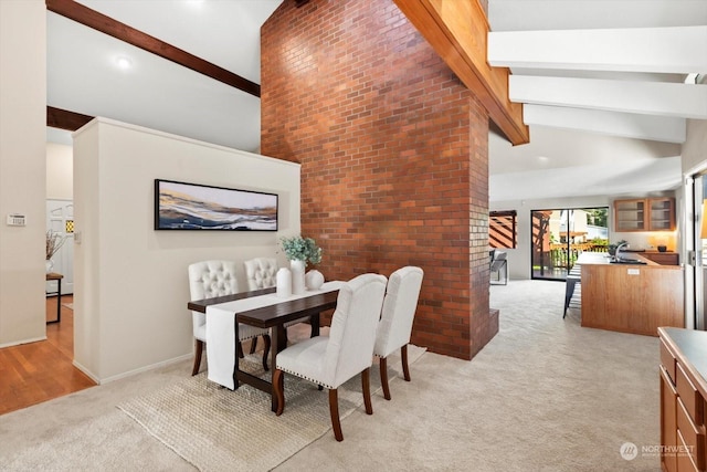 carpeted dining space featuring vaulted ceiling with beams