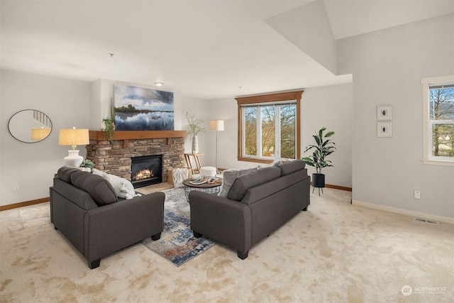 carpeted living room featuring vaulted ceiling, a stone fireplace, and plenty of natural light