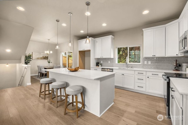 kitchen featuring a center island, white cabinets, stainless steel appliances, and light hardwood / wood-style flooring