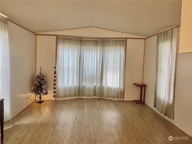 empty room featuring wood-type flooring and vaulted ceiling