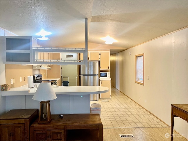 kitchen featuring kitchen peninsula, appliances with stainless steel finishes, a textured ceiling, vaulted ceiling, and light hardwood / wood-style floors