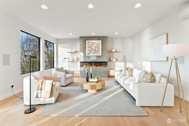 living room featuring a fireplace, light wood-type flooring, and an AC wall unit